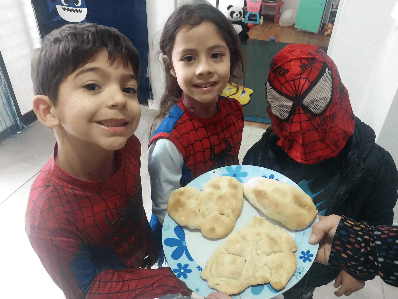 Niños disfrazados mostrando sonrientes un plato con los panes que hornearon.
